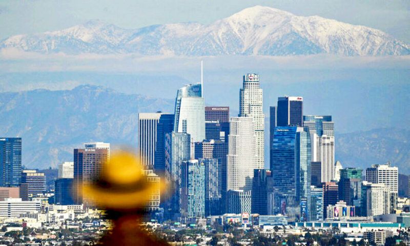 A person looks toward snow-topped mountains behind the Los Angeles downtown skyline following heavy rains, as seen from the Kenneth Hahn State Recreation Area in Los Angeles, Calif., on Dec. 15, 2021. (Patrick T. Fallon/AFP via Getty Images)