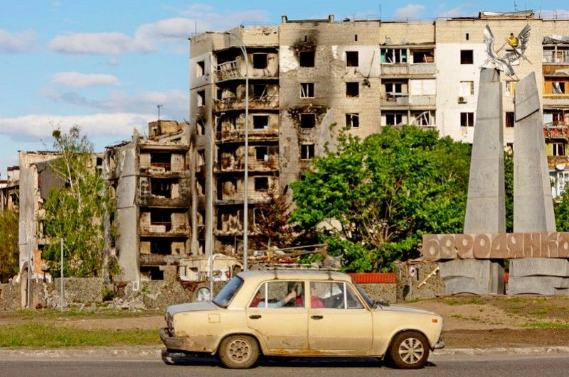 A car drives past in front of destroyed buildings, amid Russia's invasion of Ukraine