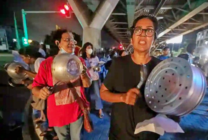 Sri Lankan women bang kitchen pots in a night-time protest at a crossroads