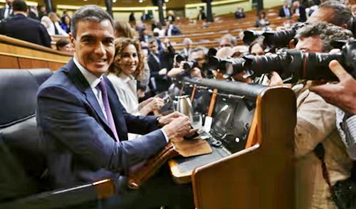 A smiling Sánchez surrounded by fellow politicians and photographers