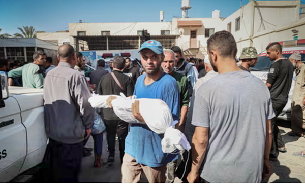 A Palestinian man carries the body of a child killed in an Israeli attack from the morgue of al-Aqsa hospital in central Gaza.