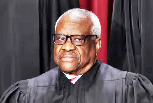 A man wearing a black robe and glasses looks off to the side